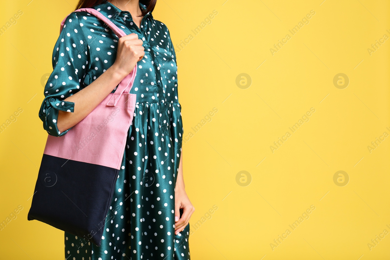 Photo of Young woman with textile bag on yellow background, closeup. Space for text