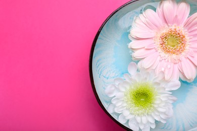 Photo of Beautiful composition with bowl of water and flowers on pink background, top view with space for text. Spa treatment