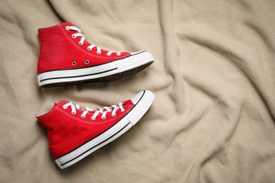 Photo of Pair of new stylish red sneakers on beige cloth, flat lay. Space for text