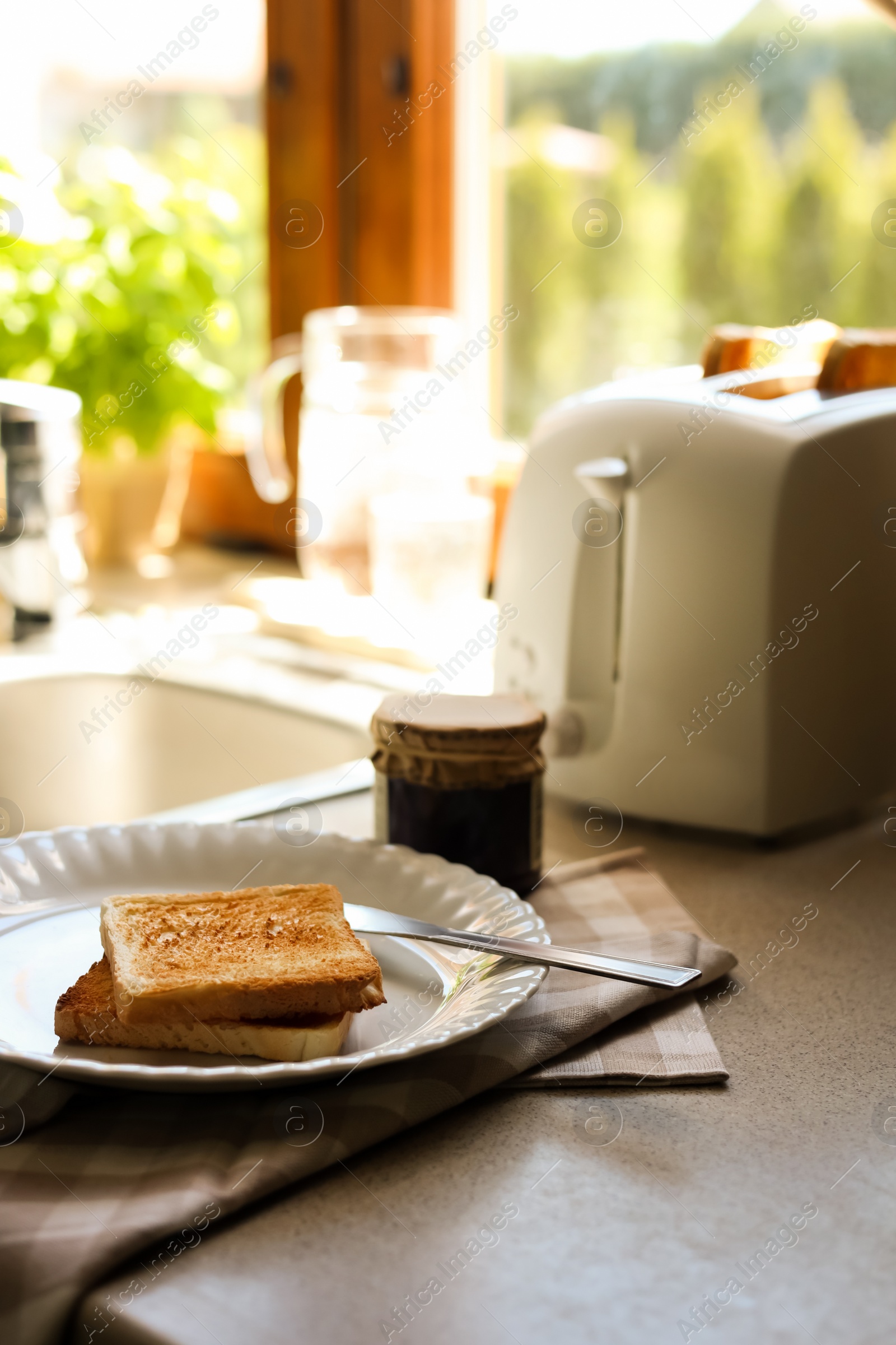 Photo of Tasty toasts and jar of jam on countertop in kitchen, space for text