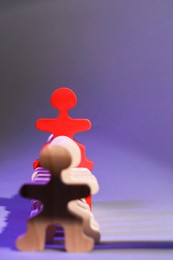 Photo of Wooden figures with red one on purple background, space for text. Recruiter searching employee