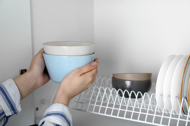 Photo of Woman taking ceramic bowls from drying rack, closeup