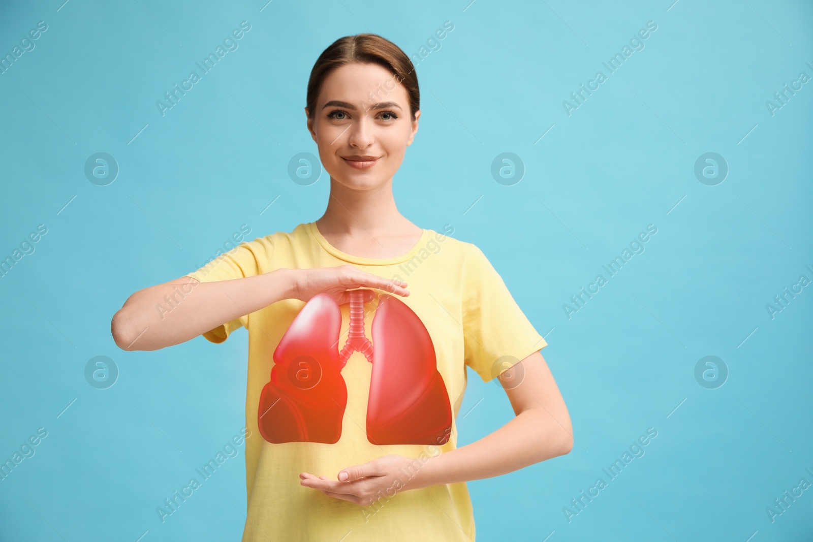 Image of Young woman holding hands near chest with illustration of lungs on turquoise background, closeup