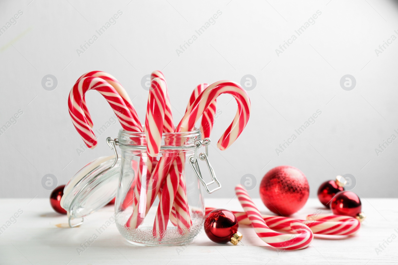 Photo of Many sweet candy canes and Christmas decor on white wooden table. Space for text