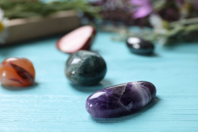 Photo of Healing gemstones on light blue wooden table, closeup