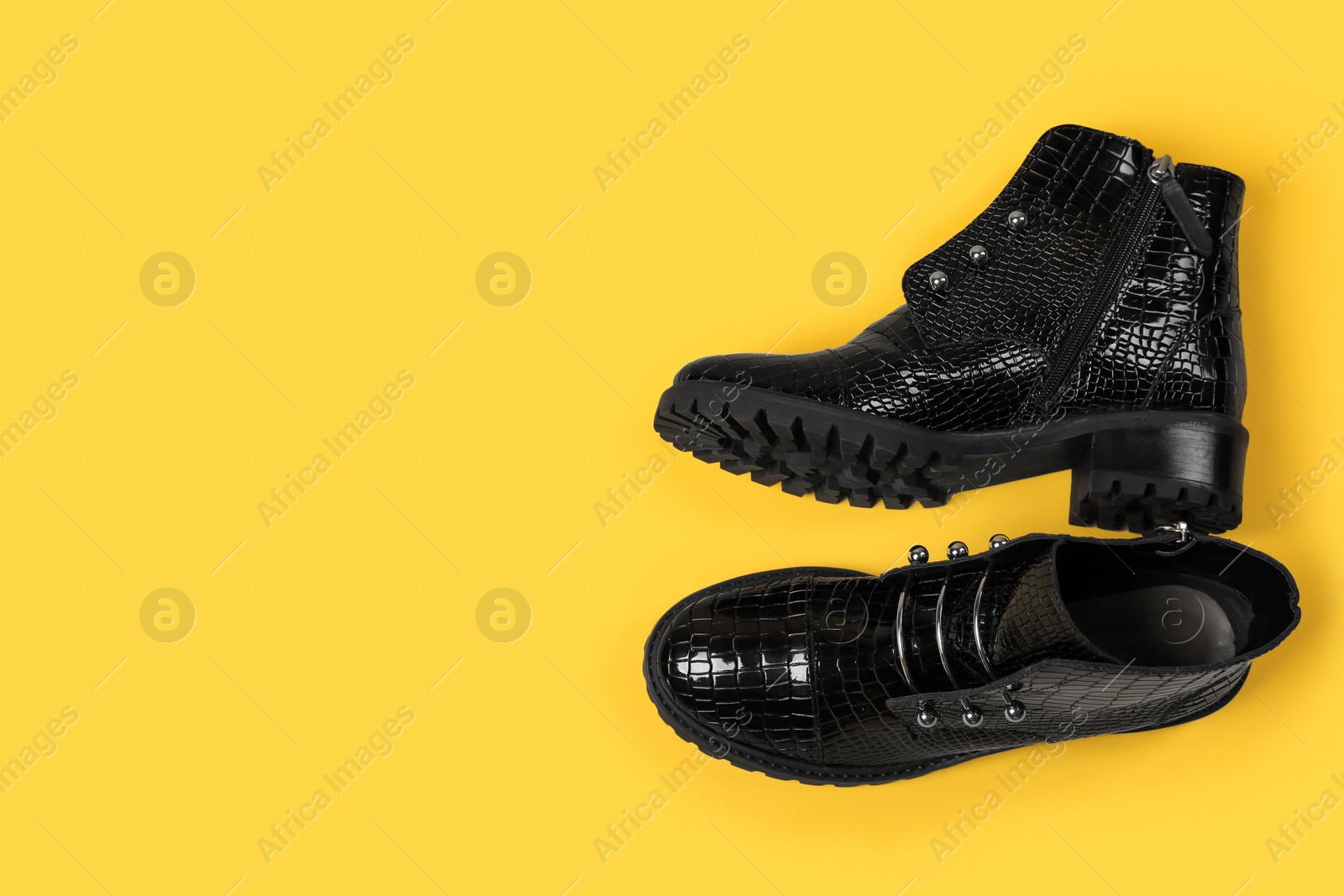 Photo of Pair of stylish ankle boots on yellow background, top view. Space for text