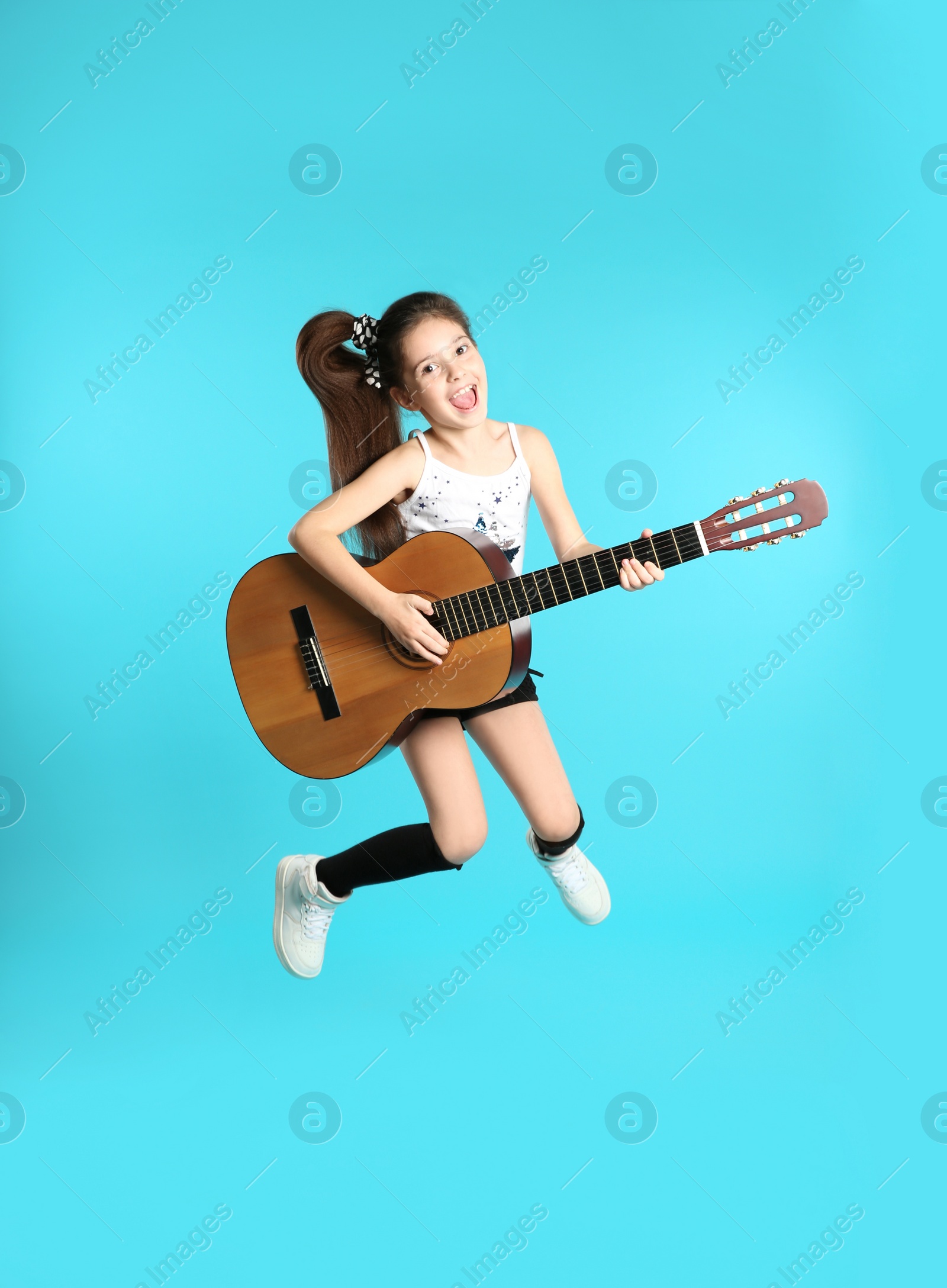 Photo of Cute little girl playing guitar on color background