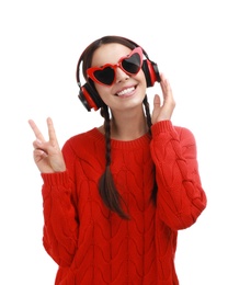 Young woman wearing heart shaped glasses listening to music on white background