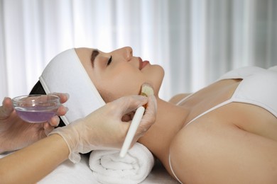 Photo of Young woman during face peeling procedure in salon