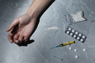 Photo of Addicted man and different hard drugs on grey marble table, top view