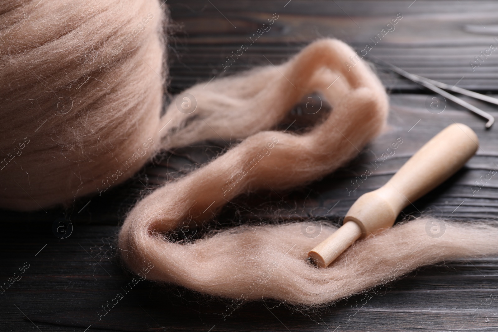 Photo of Beige felting wool and needle holder on wooden table, closeup
