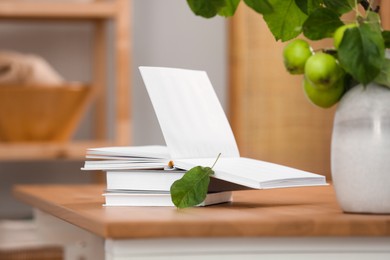 Open book and leaf on wooden table indoors