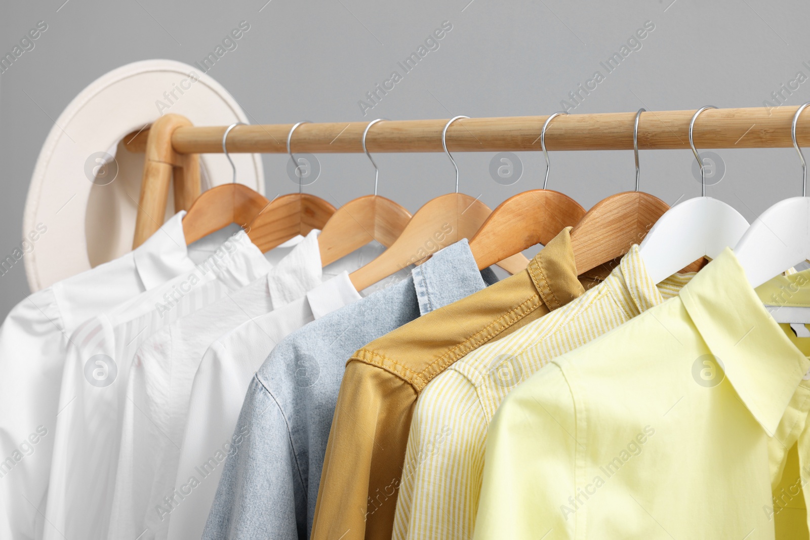 Photo of Rack with different stylish shirts against grey background, closeup. Organizing clothes