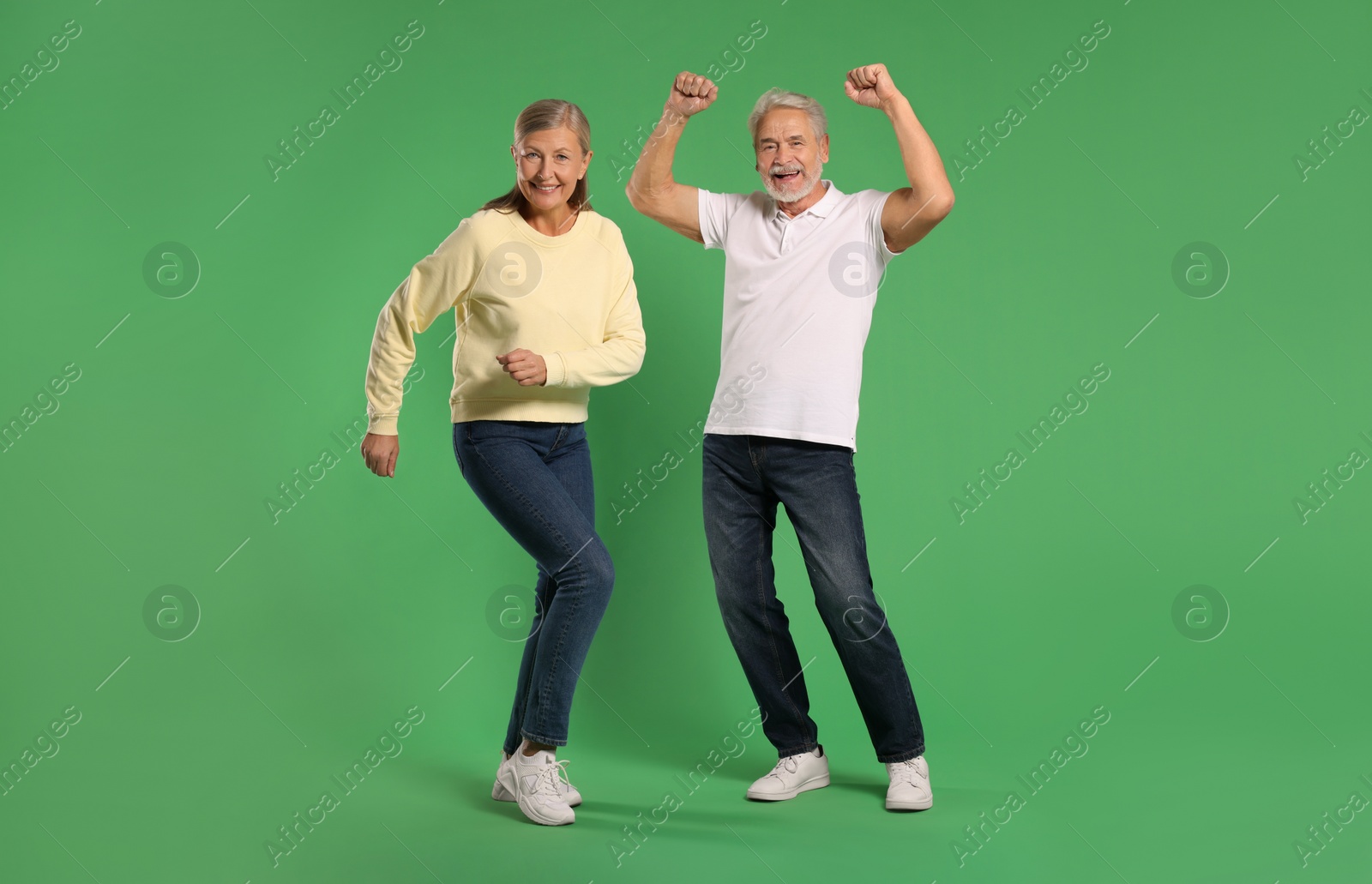 Photo of Senior couple dancing together on green background