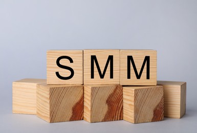 Photo of Wooden cubes with abbreviation SMM (Social media marketing) on grey background