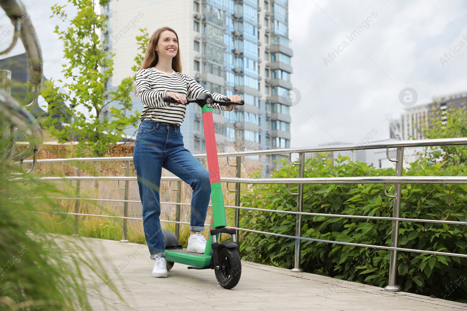 Photo of Happy woman with modern electric kick scooter on city street, space for text