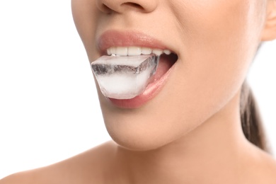 Young woman holding ice cube in mouth on white background, closeup