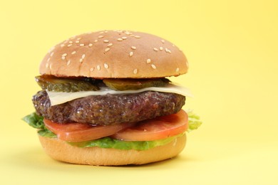Photo of Burger with delicious patty on yellow background, closeup