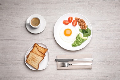 Photo of Tasty breakfast with fried egg, toasts and coffee served on white wooden table, flat lay