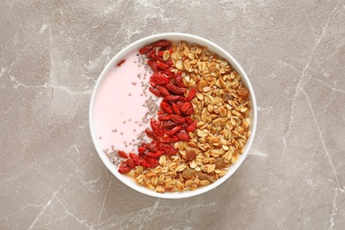 Photo of Smoothie bowl with goji berries on beige marble table, top view