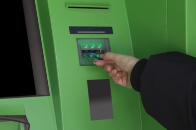 Photo of Woman inserting credit card into green cash machine, closeup
