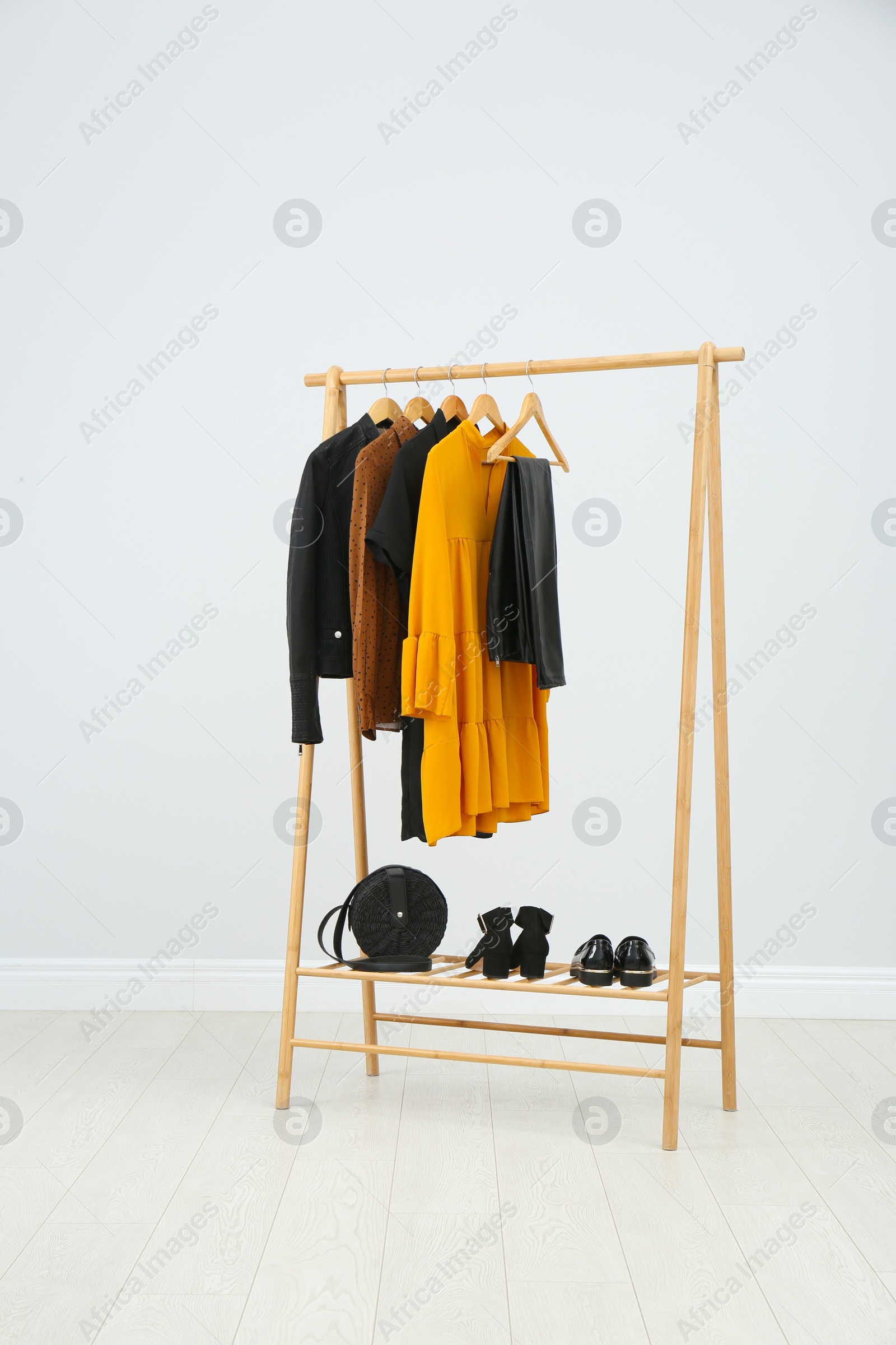 Photo of Wooden rack with stylish clothes in room