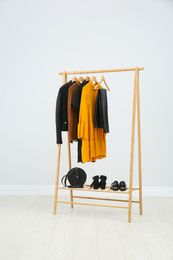 Photo of Wooden rack with stylish clothes in room