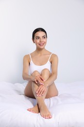 Photo of Young woman showing smooth skin after epilation on bed