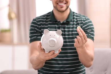 Photo of Man with piggy bank and money at home
