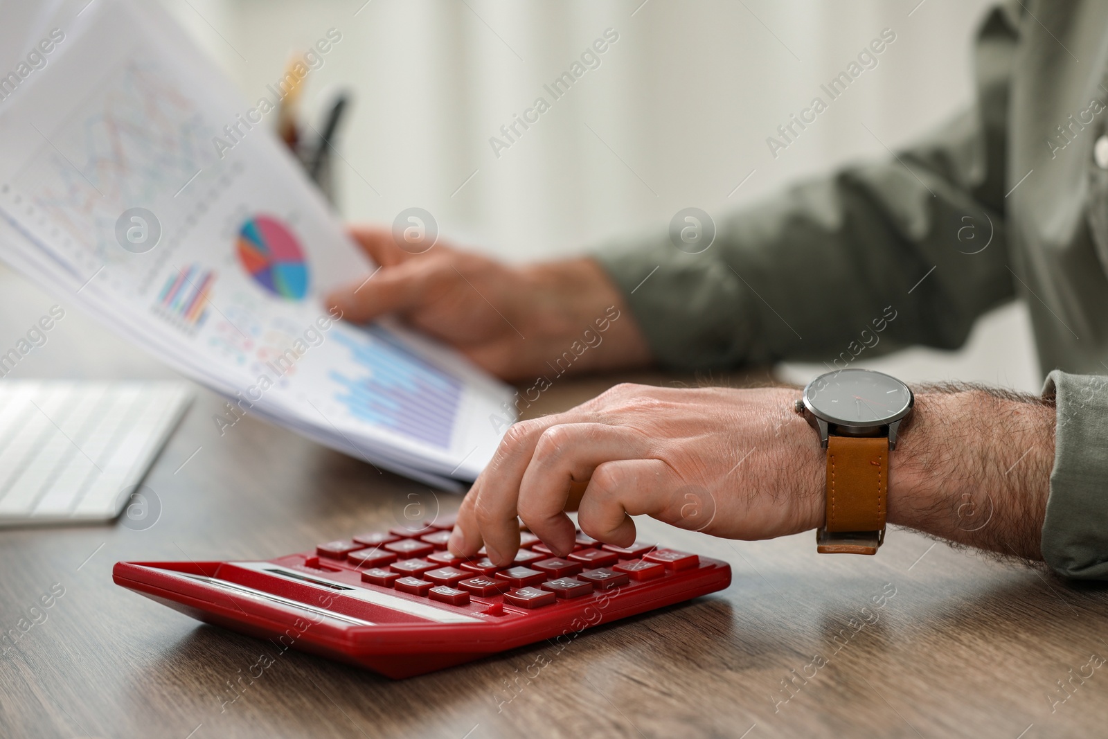 Photo of Professional accountant using calculator at wooden desk, closeup