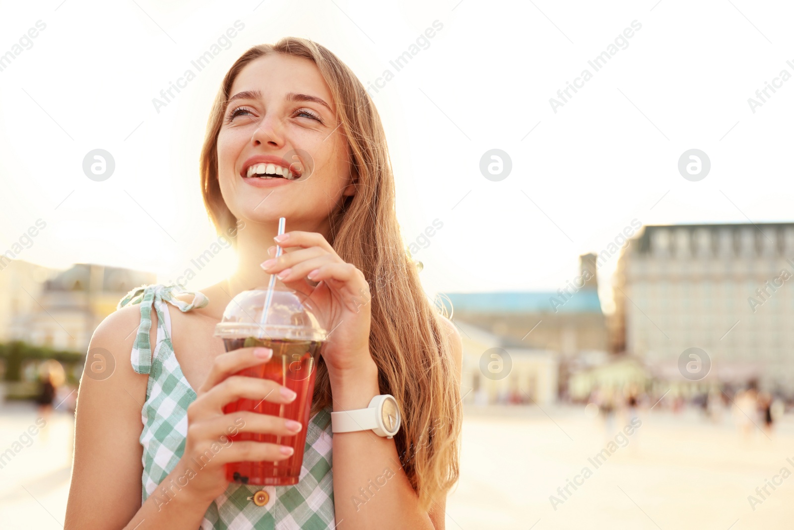 Photo of Young woman with refreshing drink on city street. Space for text