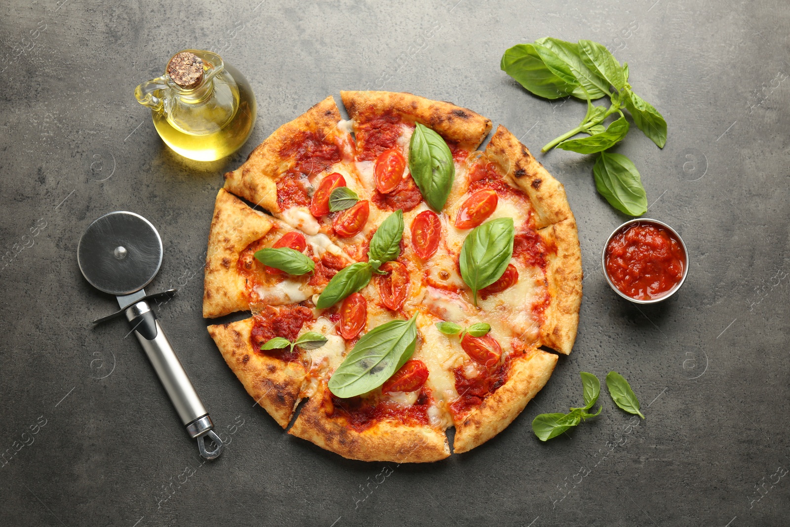 Photo of Delicious Margherita pizza, ingredients and cutter on grey table, top view