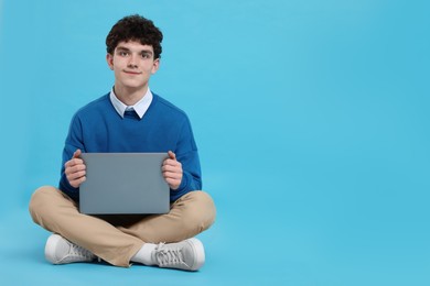 Photo of Portrait of student with laptop on light blue background. Space for text