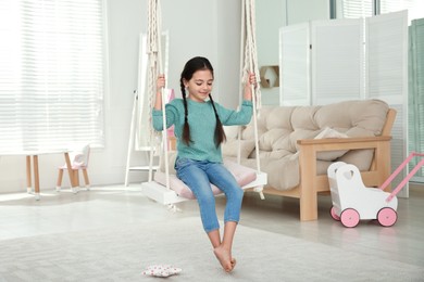 Photo of Cute little girl playing on swing at home