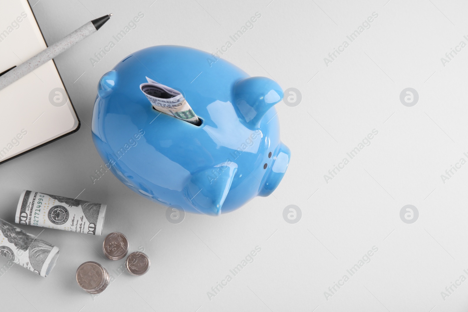 Photo of Financial savings. Piggy bank, dollar banknotes, coins and stationery on grey background, flat lay. Space for text