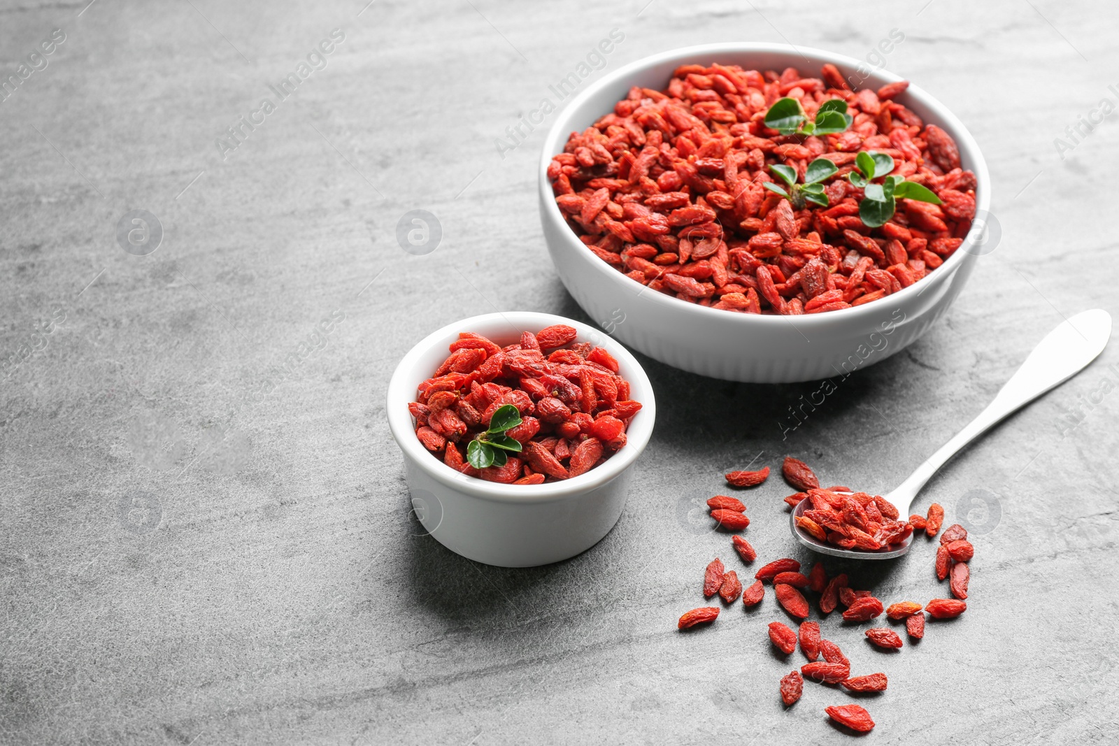Photo of Composition with dried goji berries on grey table, space for text. Healthy superfood