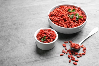 Photo of Composition with dried goji berries on grey table, space for text. Healthy superfood