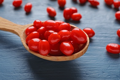 Photo of Fresh ripe goji berries in spoon on blue wooden table