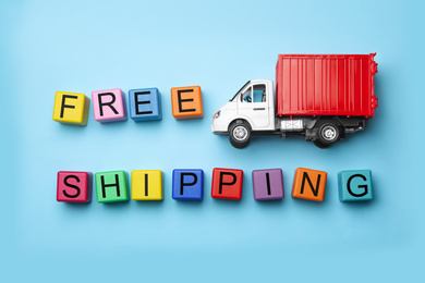 Photo of Toy truck with words FREE DELIVERY on blue background, flat lay. Logistics and wholesale concept