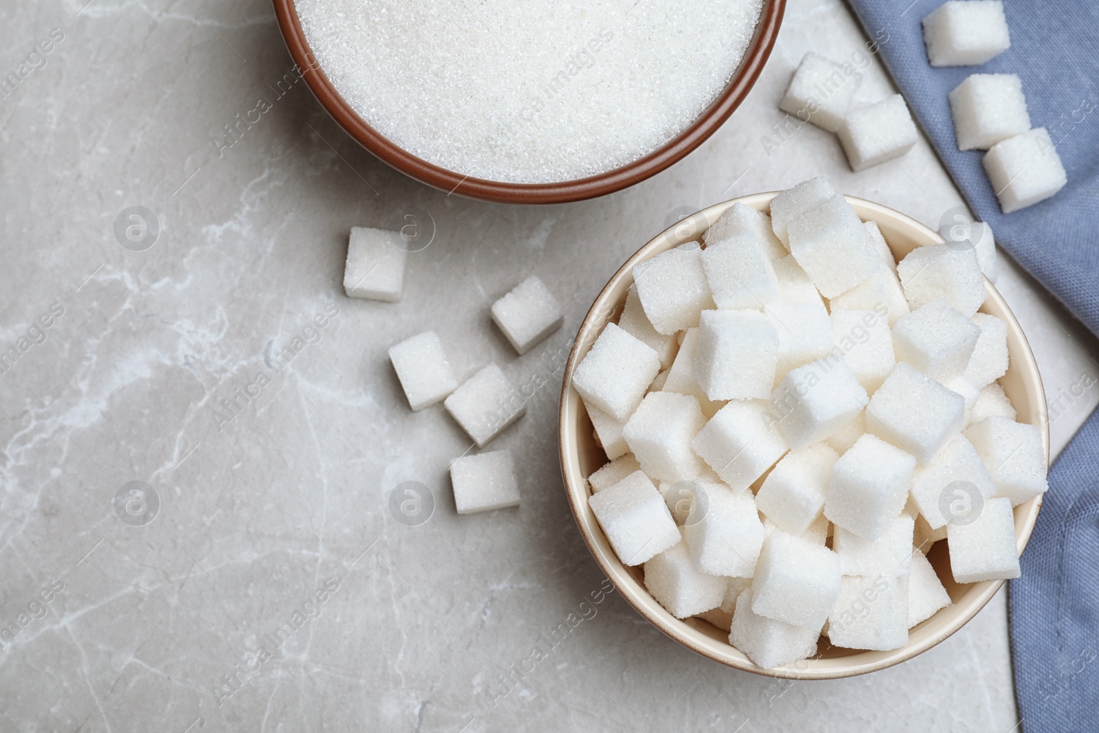 Refined sugar sand and cubes on grey table, flat lay Photo of Refined sugar sand and cubes on grey table, flat lay