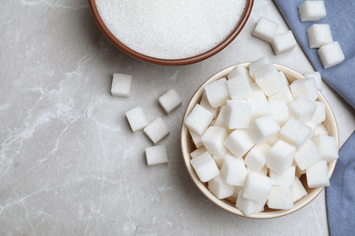 Photo of Refined sugar sand and cubes on grey table, flat lay