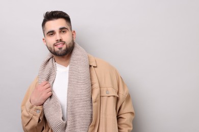 Photo of Smiling man in warm scarf on light grey background. Space for text