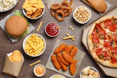 Photo of French fries, chips and other fast food on wooden table, flat lay