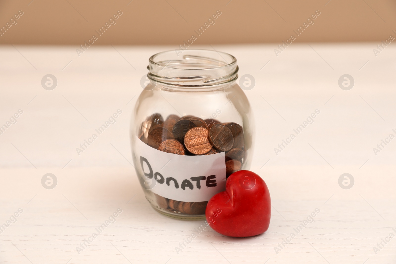 Photo of Red heart and donation jar with coins on table