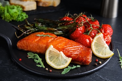 Photo of Delicious cooked salmon and vegetables on black table, closeup. Healthy meals from air fryer