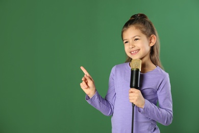 Photo of Cute funny girl with microphone on color background. Space for text