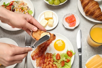 Photo of Woman spreading butter on toast at table, closeup. Buffet service