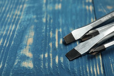 Photo of Set of screwdrivers on blue wooden table, closeup. Space for text