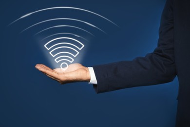 Image of Man holding Wi Fi symbol in hand on dark blue background, closeup