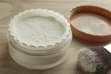 Photo of Rice loose face powder and makeup brush on brown table, closeup